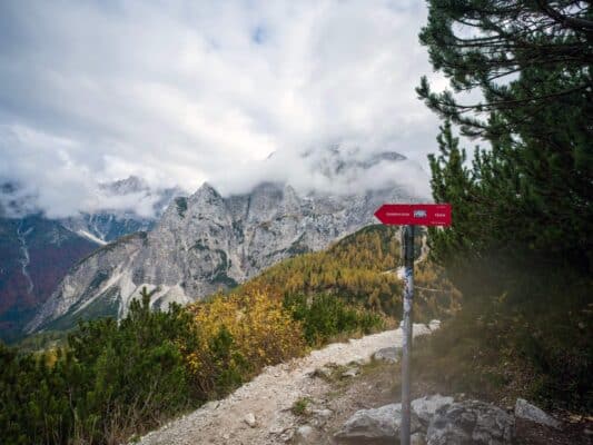 Cartello del sentiero del rifugio con paesaggio montano sullo sfondo.