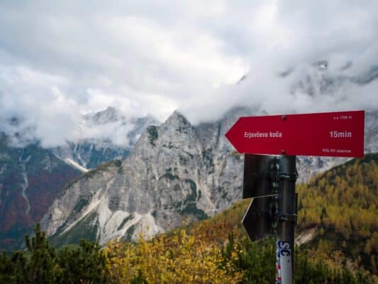 Paesaggio montano remoto con cime rocciose avvolte dalla nebbia e alberi dai colori autunnali presso il rifugio Erjavčeva.